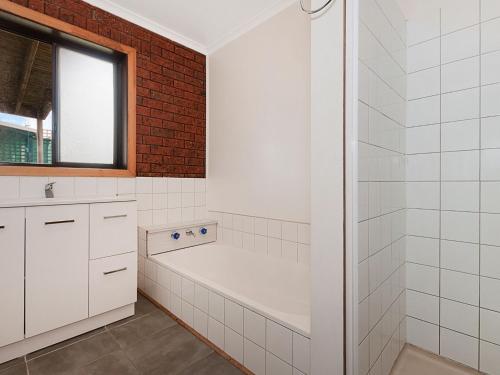 a white bathroom with a tub and a window at Ambience By The Sea in Port Fairy