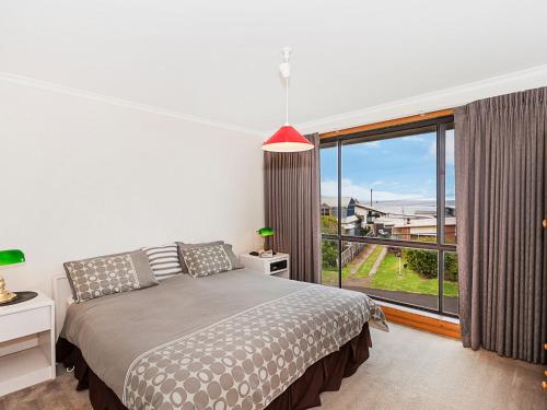 a bedroom with a bed and a large window at Ambience By The Sea in Port Fairy