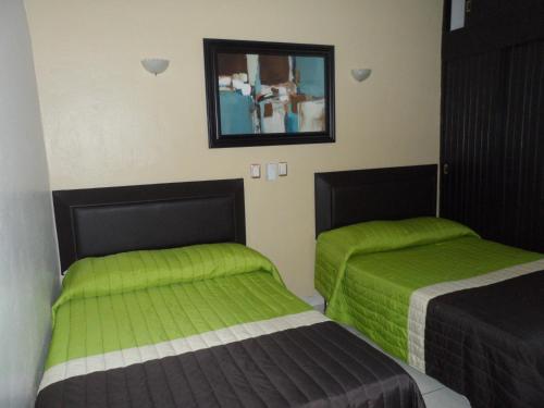 two beds in a room with green sheets at Hotel Fernando in Tuxtla Gutiérrez
