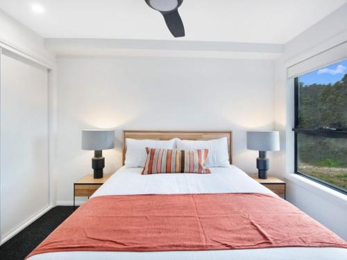 a bedroom with a large bed and a window at Black Diamond Retreat - Luxury 3BR Home l Lake Views l Fire Pit l WiFi l Bath in Jindabyne