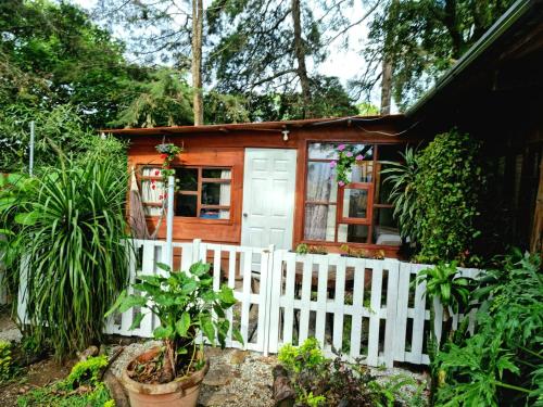 a small wooden house with a white fence at CABAÑAS EN ZONA 16 in Guatemala