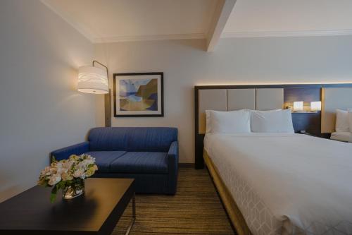 a hotel room with a bed and a blue chair at Holiday Inn Express & Suites Santa Clara - Silicon Valley by IHG in Santa Clara