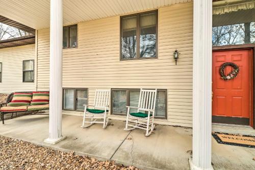 two chairs on the porch of a house with a red door at 40-Acre Poplar Bluff Nature Lovers Paradise! in Poplar Bluff