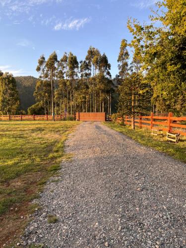 a gravel road in a field with a fence at Mehuín el Remanso de Paz in Mehuín