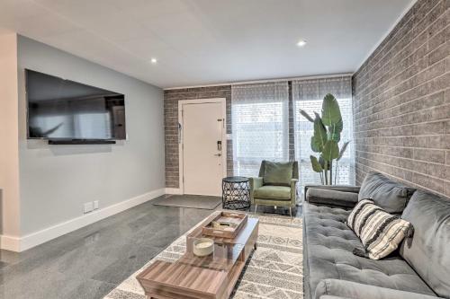 a living room with a gray couch and a brick wall at Walk to Fashion Square! Snowbird Condo with Pool in Scottsdale