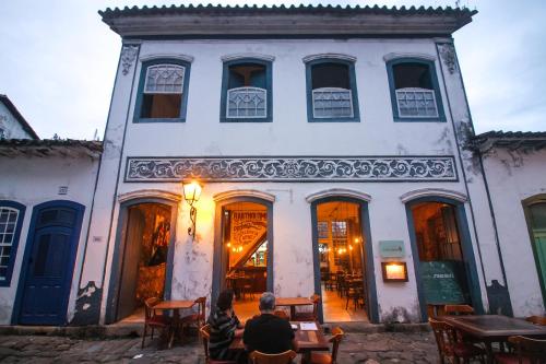 two people sitting in front of a white building at Pousada Bartholomeu in Paraty