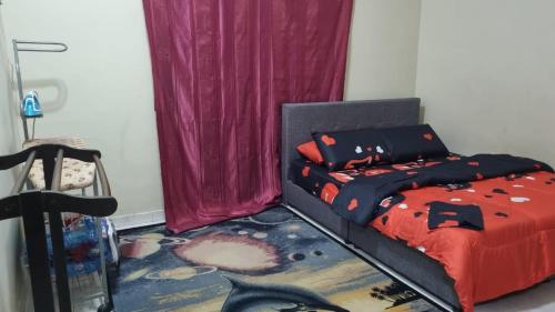 a bedroom with a bed with a red comforter at INAP DESA ABYKAMSHAR in Merlimau