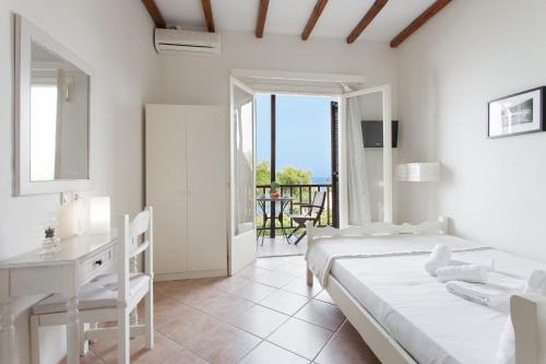 a bedroom with two beds and a desk and a balcony at Pansion Martha in Agios Ioannis Pelio