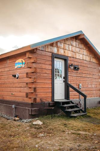 a wooden cabin with a door and a chair outside at Alaskan Suites in Homer