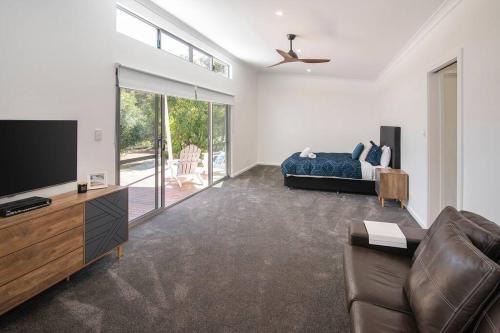 a living room with a bed and a tv and a couch at Blue Haven Margaret River tranquil bush retreat in Margaret River Town