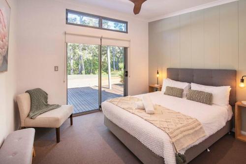 マーガレットリバーにあるBlue Haven Margaret River tranquil bush retreatのベッドとガラスの引き戸のある寝室