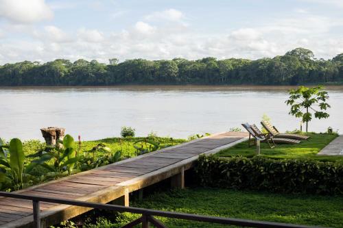 a wooden bridge over a river with two chairs at Enai in Puerto Maldonado
