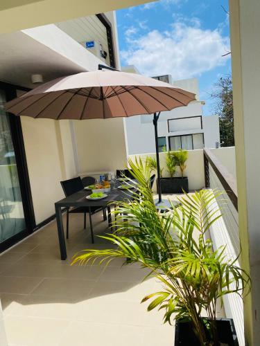 a patio with a table and an umbrella on a balcony at Superbe apt 2 chambres Mont Choisy Beach by Lov in Mont Choisy