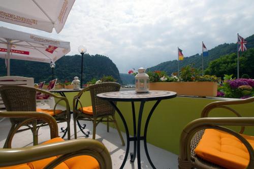 a patio with tables and chairs and a view of the water at Hotel Cafe Restaurant Loreleyblick in Sankt Goar