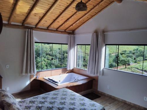 a bedroom with a tub in a room with windows at Hospedagem Colinas Chalé 2 in Aiuruoca