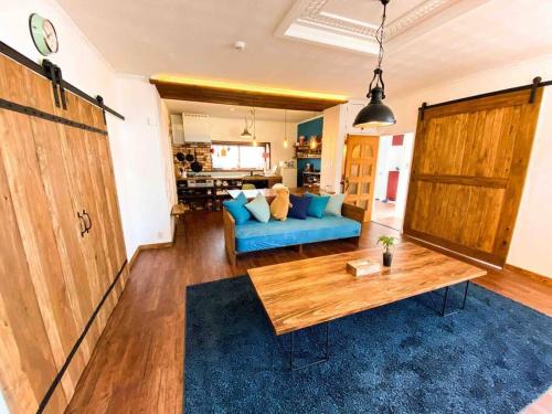a living room with a blue couch and a wooden table at Poroto Base ウポポイまで徒歩2分 in Shiraoi