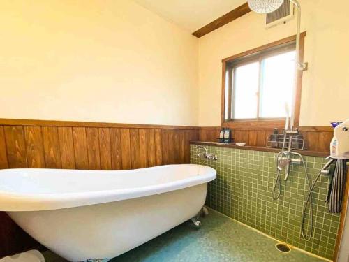 a bathroom with a tub and a green tiled wall at Poroto Base ウポポイまで徒歩2分 in Shiraoi