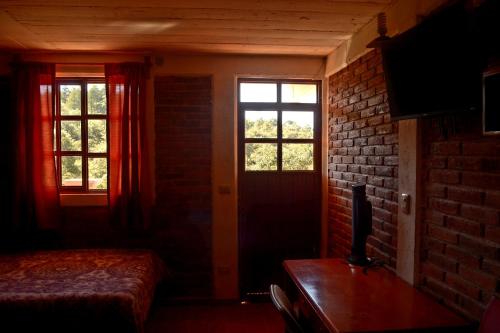 a bedroom with two windows and a table with a television at Casa de Descanso Chignahuapan in Chignahuapan