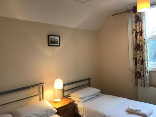 a bedroom with two beds and a lamp and a window at Atlas Oxford House in Oxford