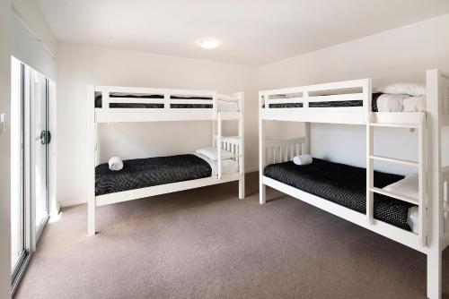 a bedroom with white bunk beds in a room at Bo'Vine Holiday Apartment in Cowaramup