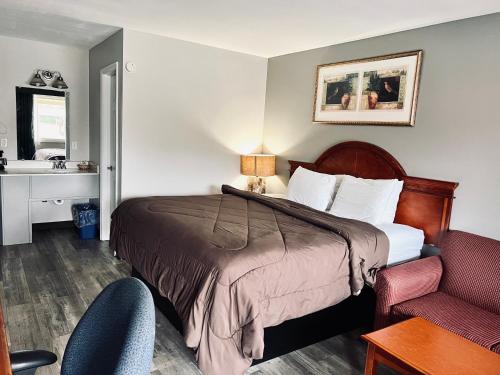 a hotel room with a bed and a desk and a chair at Ozark Inn & Suites in Ozark