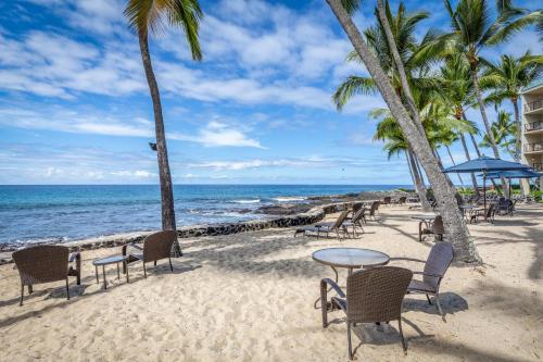 a beach with chairs and tables and the ocean at Aston Kona By The Sea in Kailua-Kona