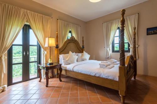 Villa Malinee Khao Yai في Ban Tha Chang: غرفة نوم بسرير كبير في غرفة بها نوافذ