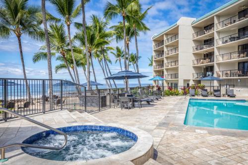a swimming pool with palm trees and a resort at Aston Kona By The Sea in Kailua-Kona