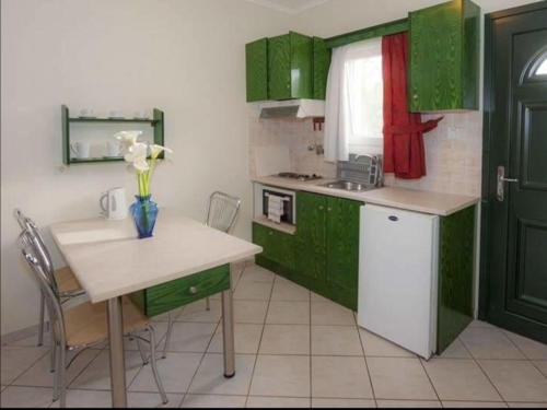 a kitchen with green cabinets and a table with flowers at L'eremo Luxury Studio in Roda
