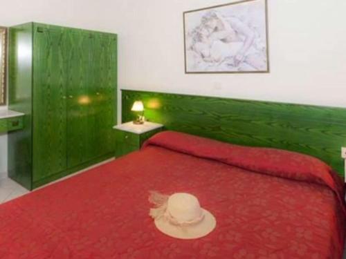 a bedroom with a red bed with a hat on it at L'eremo Luxury Studio in Roda