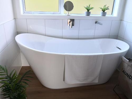 a white bath tub in a bathroom with a window at Karapiro Retreats holiday house in Cambridge