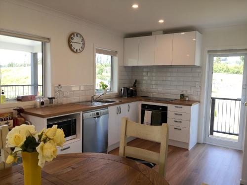a kitchen with white cabinets and a clock on the wall at Karapiro Retreats holiday house in Cambridge