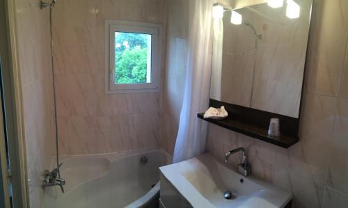 a bathroom with a tub and a sink and a mirror at Hôtel Saint Alban in Saint-Maur-des-Fossés