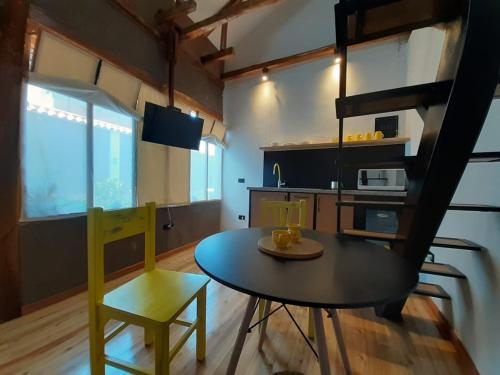 a room with a table and a chair and a kitchen at Hostal Suite Le Fabrique in Cuenca