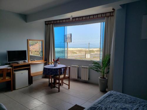 a room with a desk and a table and a window at De Rose Praia Hotel in Torres