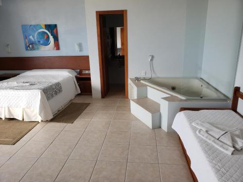 a bedroom with a bed and a bath tub at De Rose Praia Hotel in Torres