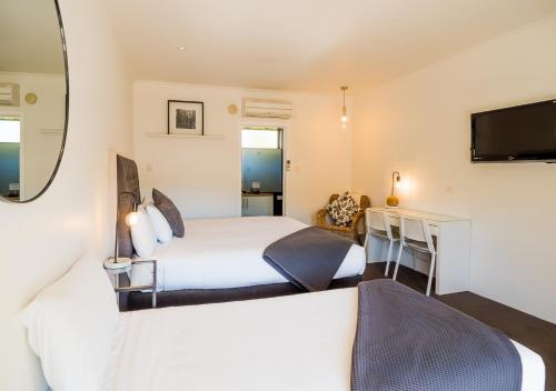 a bedroom with two beds and a desk and a television at Tower Motel Marysville in Marysville