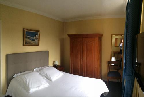 a bedroom with a white bed and a wooden cabinet at Hôtel Saint Alban in Saint-Maur-des-Fossés