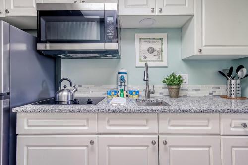 a kitchen with white cabinets and a sink and a microwave at Sea Watch Resort in Myrtle Beach