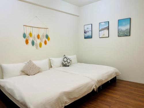 biała sypialnia z łóżkiem i zdjęciami na ścianie w obiekcie 水上雅居民宿 w mieście Hualian
