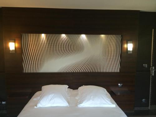 a bed with two white pillows in a room at Hôtel Saint Alban in Saint-Maur-des-Fossés