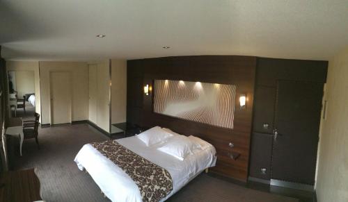 - une chambre avec un grand lit et une tête de lit en bois dans l'établissement Hôtel Saint Alban, à Saint-Maur-des-Fossés