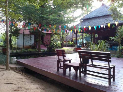 two benches and a table and chairs on a wooden deck at Banpainamhomestay in Ban Huai Thalaeng Phan