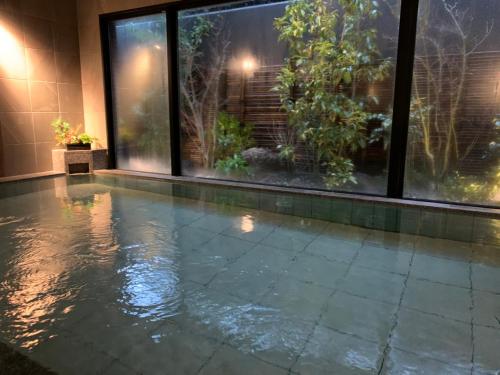 an indoor pool with water in a room with windows at Hotel Route-Inn Sakurai Ekimae in Sakurai