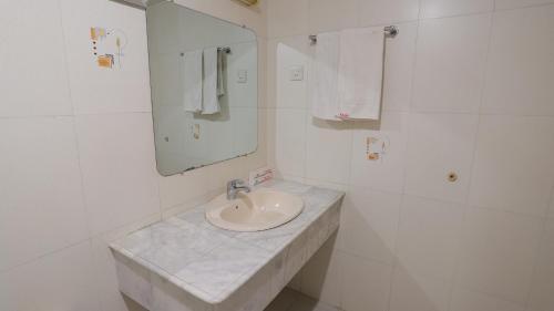 a white bathroom with a sink and a mirror at Hotel Metro International in Sylhet