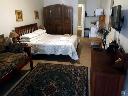 a bedroom with a bed and a tv and a couch at Bisibee Guest House in Oudtshoorn