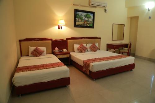 a hotel room with two beds and a mirror at Hotel Metro International in Sylhet