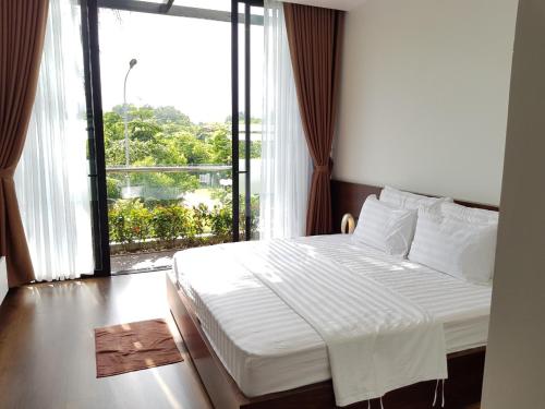 a bedroom with a bed and a large window at Flamigo Dai Lai Resort - Happy Villa in Ngọc Quang