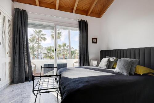 um quarto com uma cama e uma grande janela em Frontline paradise townhouse em Estepona