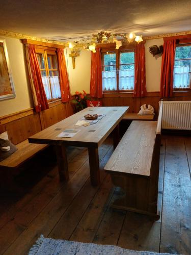 une table et un banc en bois dans une chambre avec fenêtres dans l'établissement Ferienhaus Alpenglück, à Gaicht